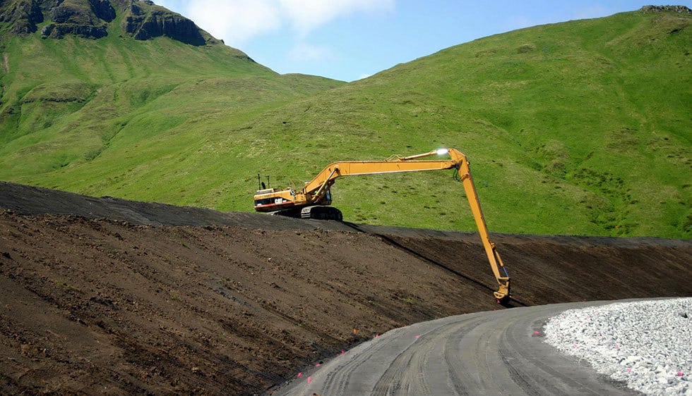 a large yellow excavator is on the side of a road