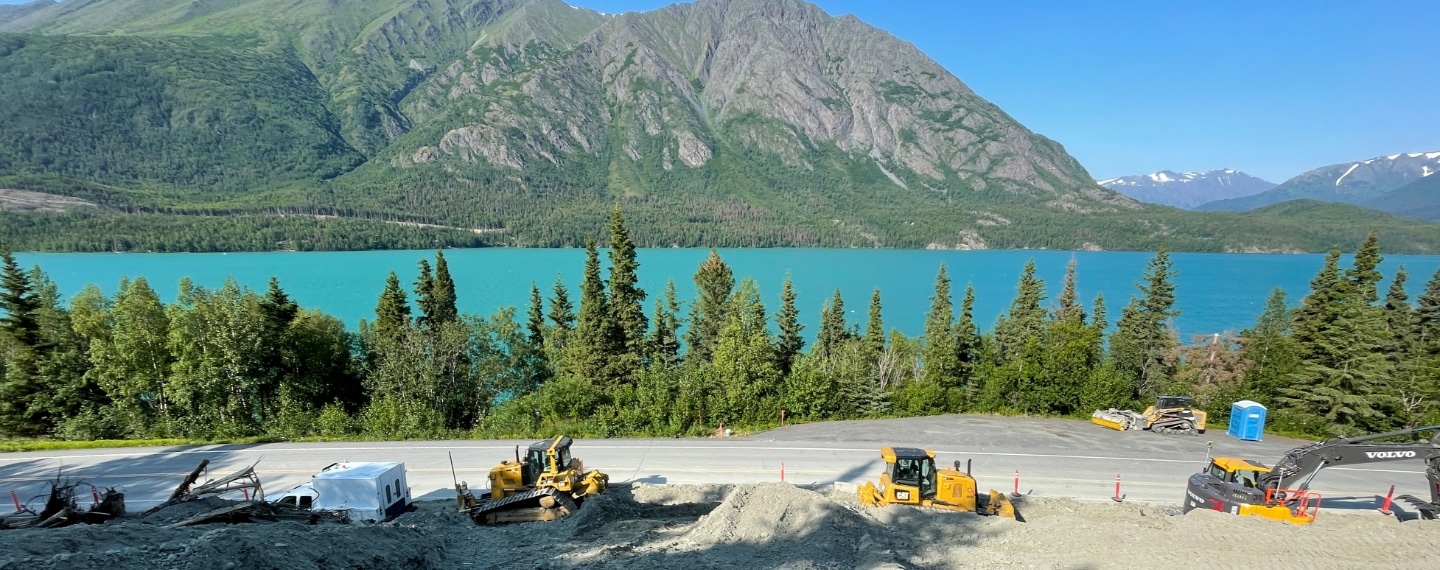GPS Alaska construction equipment at work next to beautiful Alaska lake