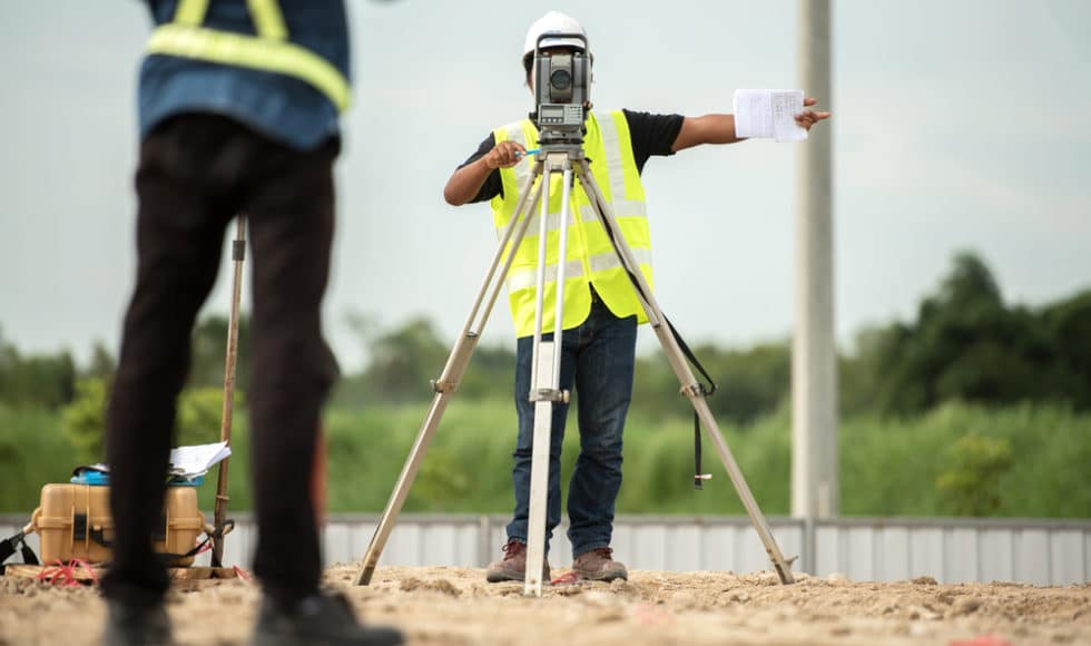 Two workmen survey a job site; gnss receivers vs total stations