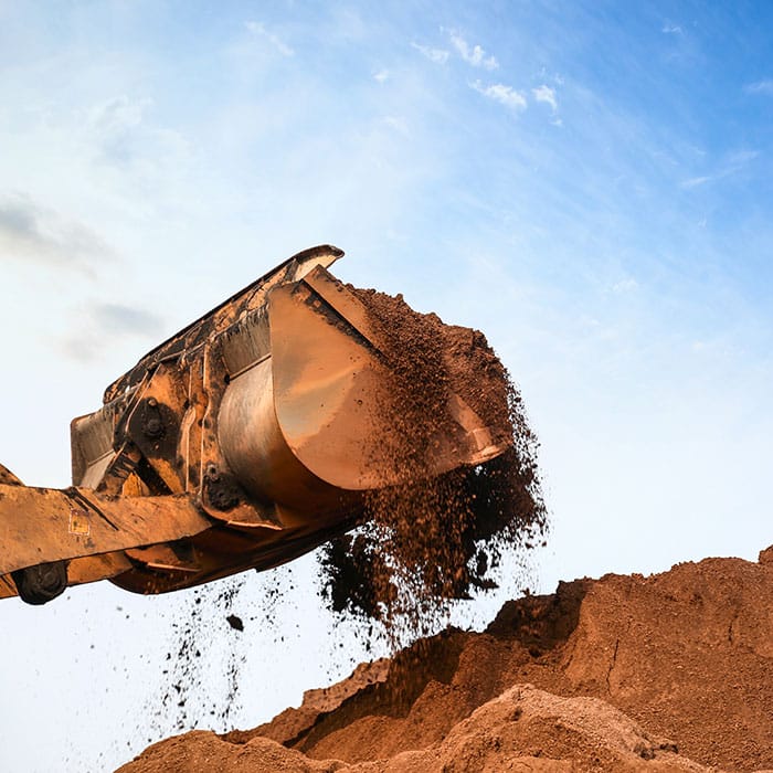 Excavator bucket hauls dirt using the iDig Grade Control System