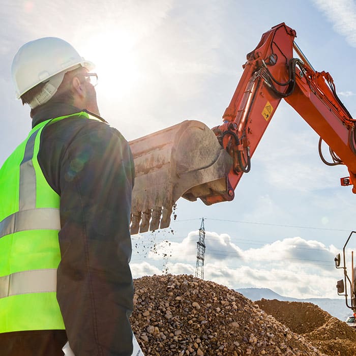 Construction worker supervises an excavator using the MC-X Platform Machine Control System